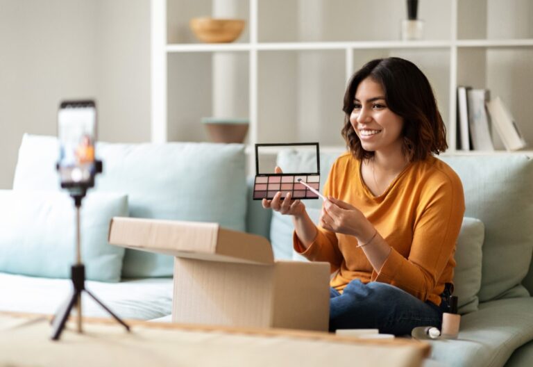 Micro Influencer ; Frau sitzt auf einem Sofa und präsentiert Makeup vor ihrer Handykamera